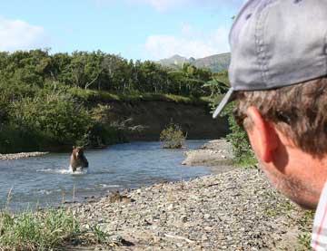 Guide watching bear in stream come close.