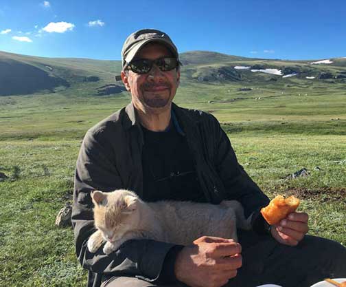 Dr. P eating breakfast with a cat on his lap
