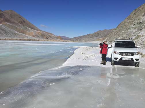 Wintertime on a frozen road in the mountains of western Mongolia along a river