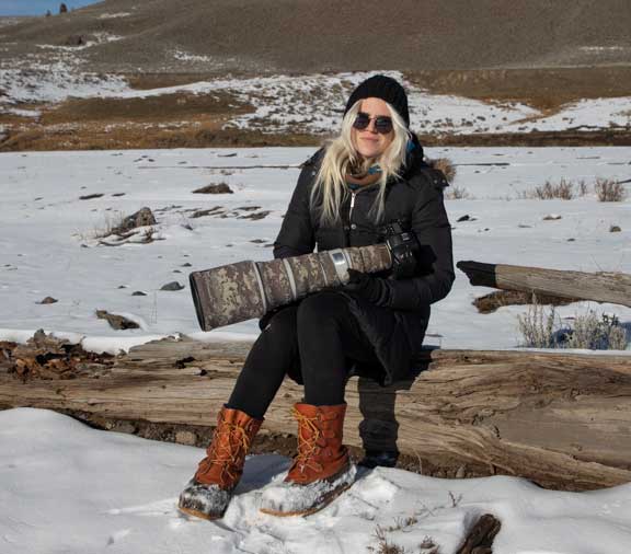 Dr. P's assistant photographer with camera and telephoto lens sitting on a log