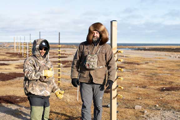 Guide standing next to electric fence